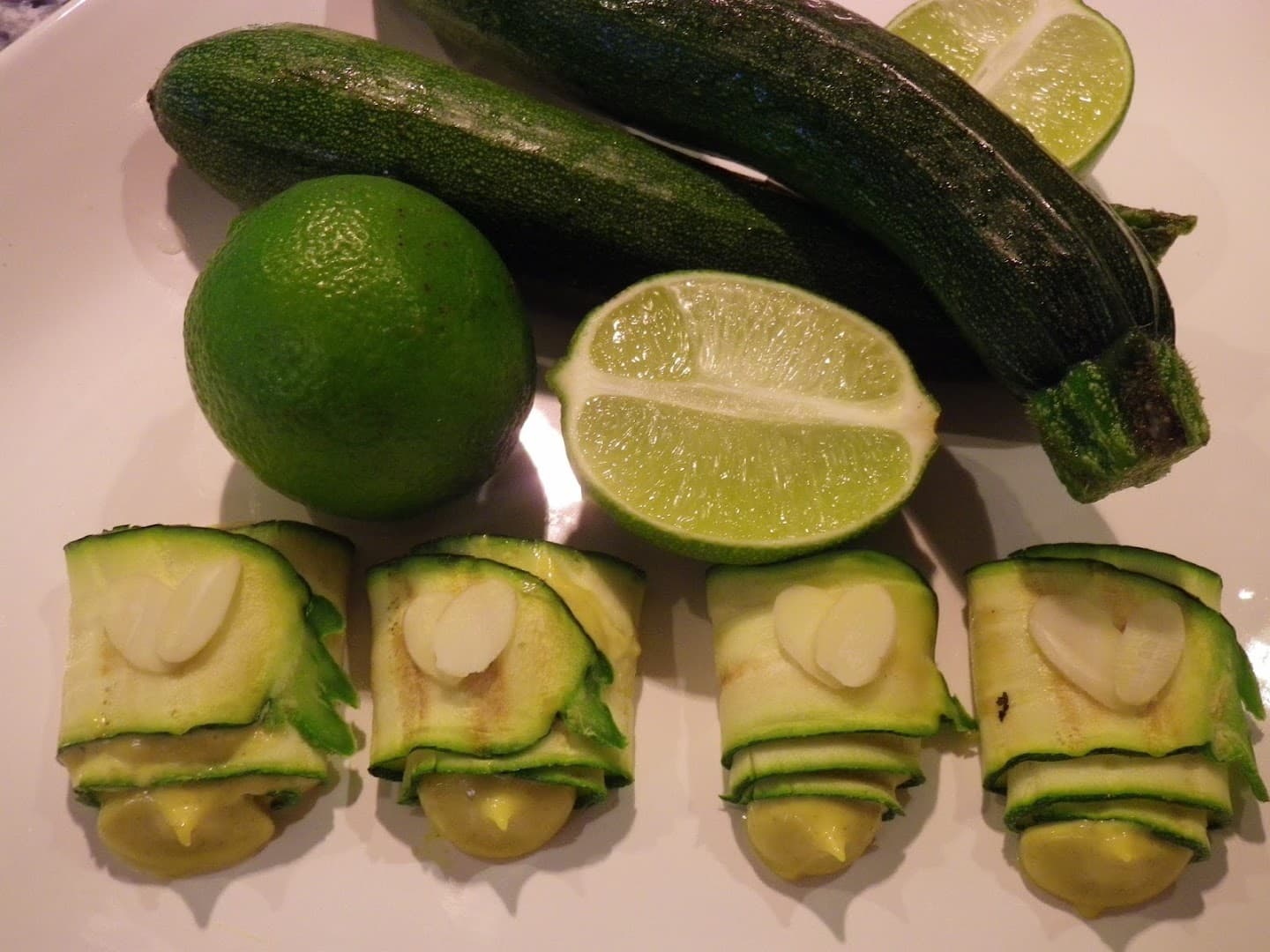 Zucchini-Röllchen mit Mandelblättchen vor Zucchini und Limetten