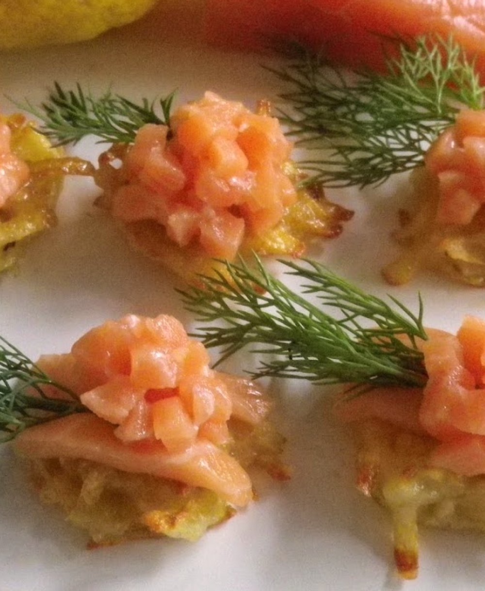 Fingerfood, Nahaufnahme: Lachstatar auf goldbraunen Rösti mit Dillzweigen auf einem weißen Teller